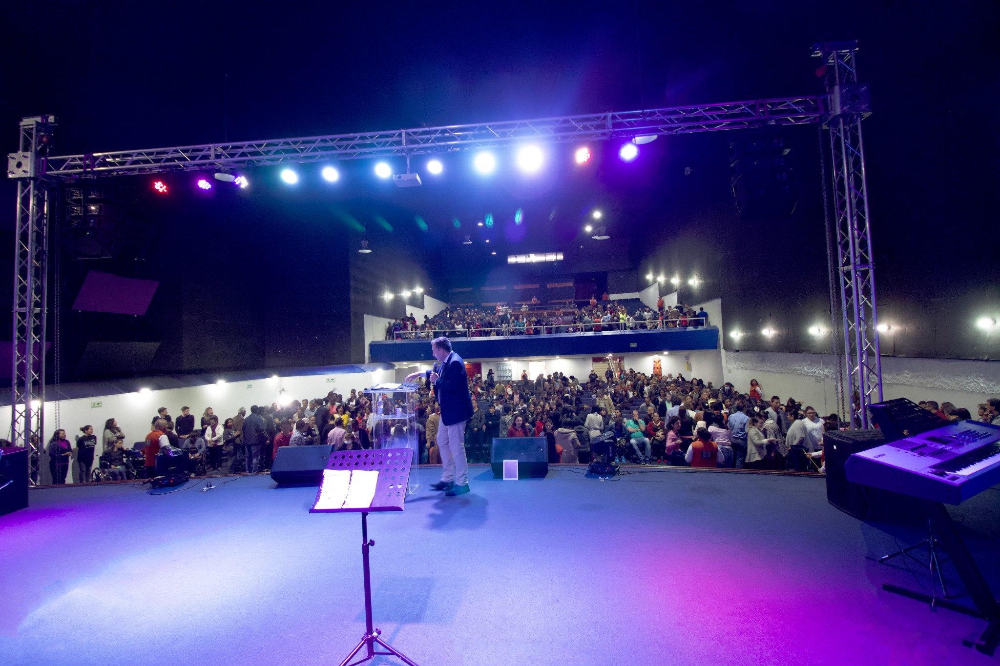 Vista desde el escenario de un auditorio lleno durante una reunión cristiana.