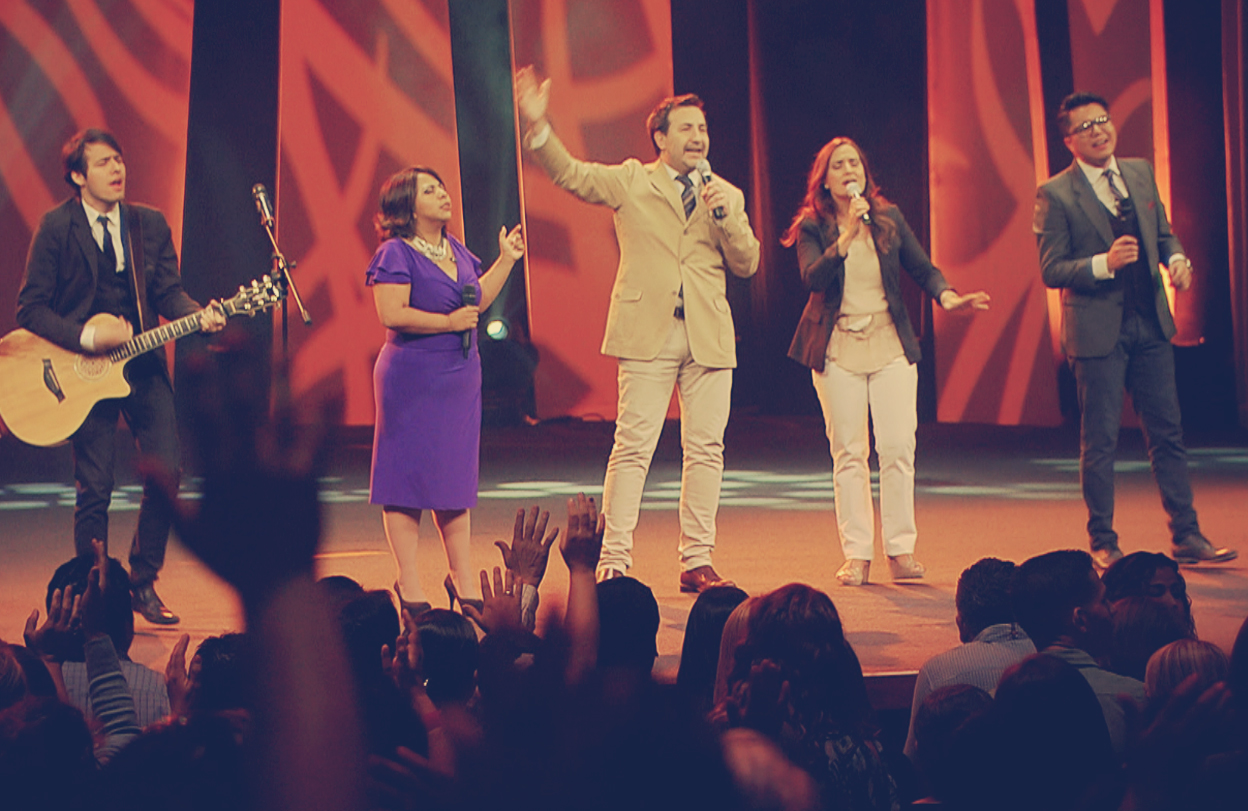 Equipo de alabanza en el escenario junto a Manuel y Toñy durante una reunión cristiana.