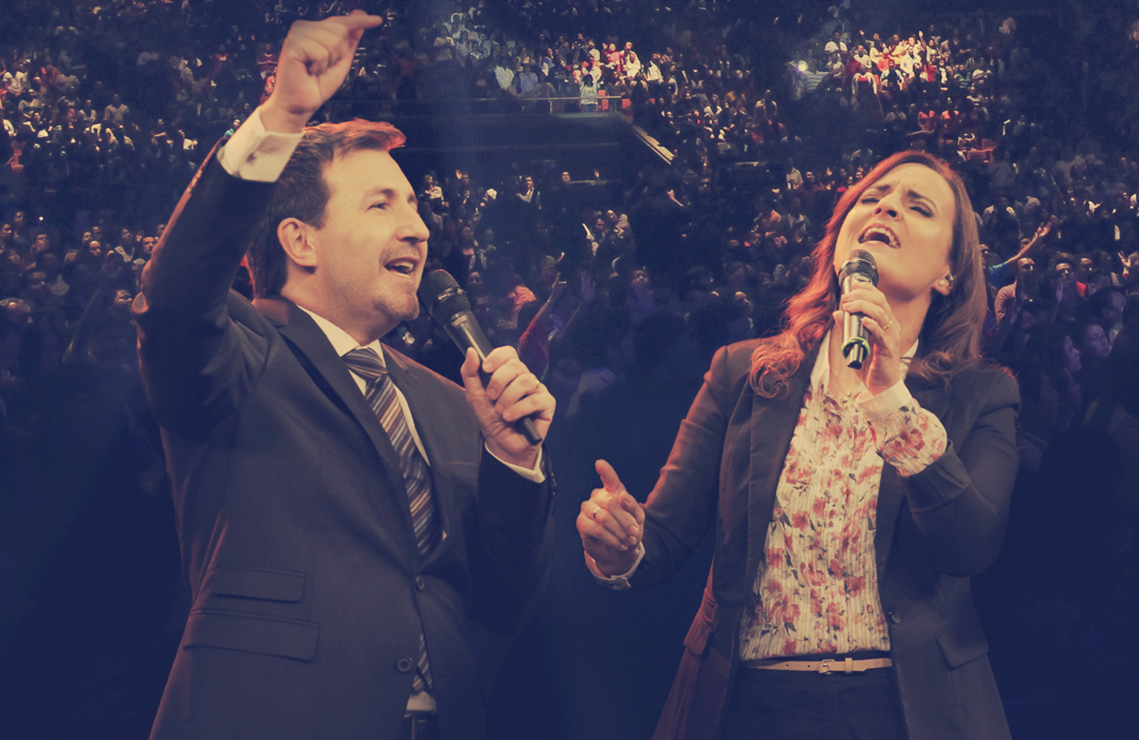 Manuel y Toñy cantando y ministrando ante una gran congregación en un auditorio.