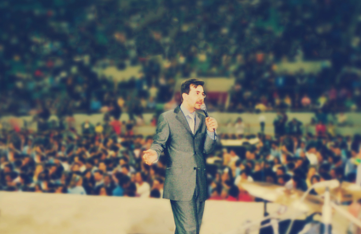 Predicador hablando a una multitud durante un gran encuentro cristiano.