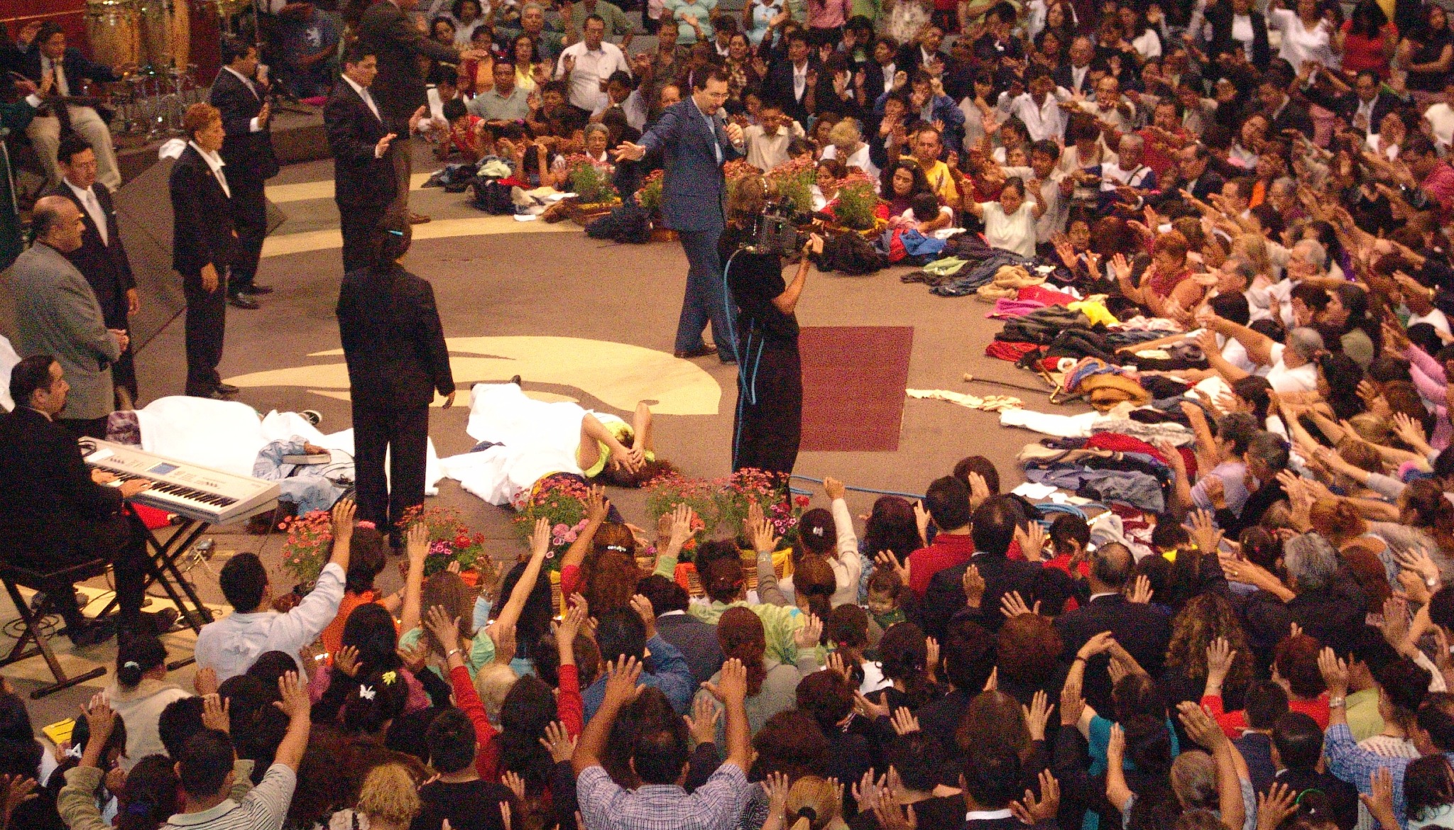Gran congregación participando en un momento de oración durante una reunión cristiana.