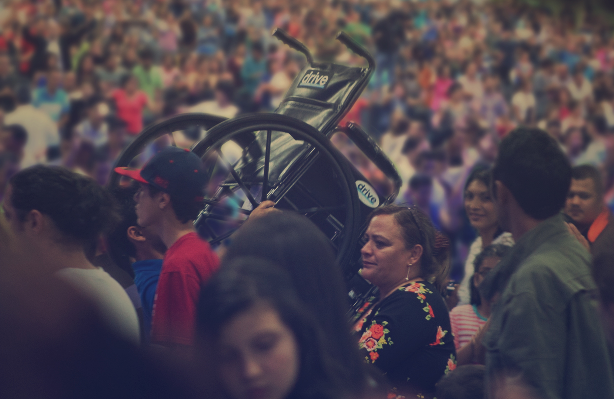 Una silla de ruedas elevada entre la congregación durante un momento de celebración y testimonio de fe.